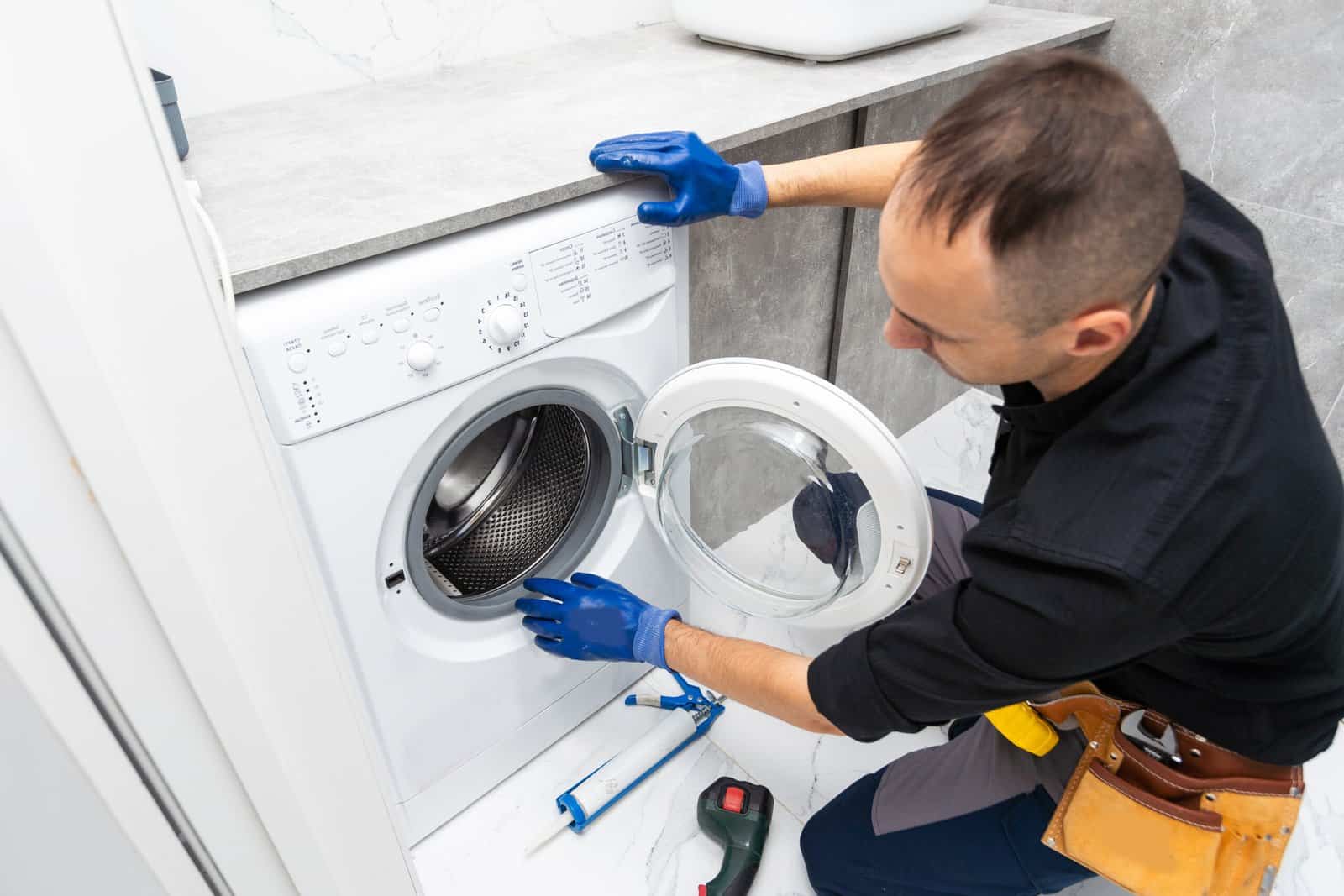 Plumber fixing dryer on white background