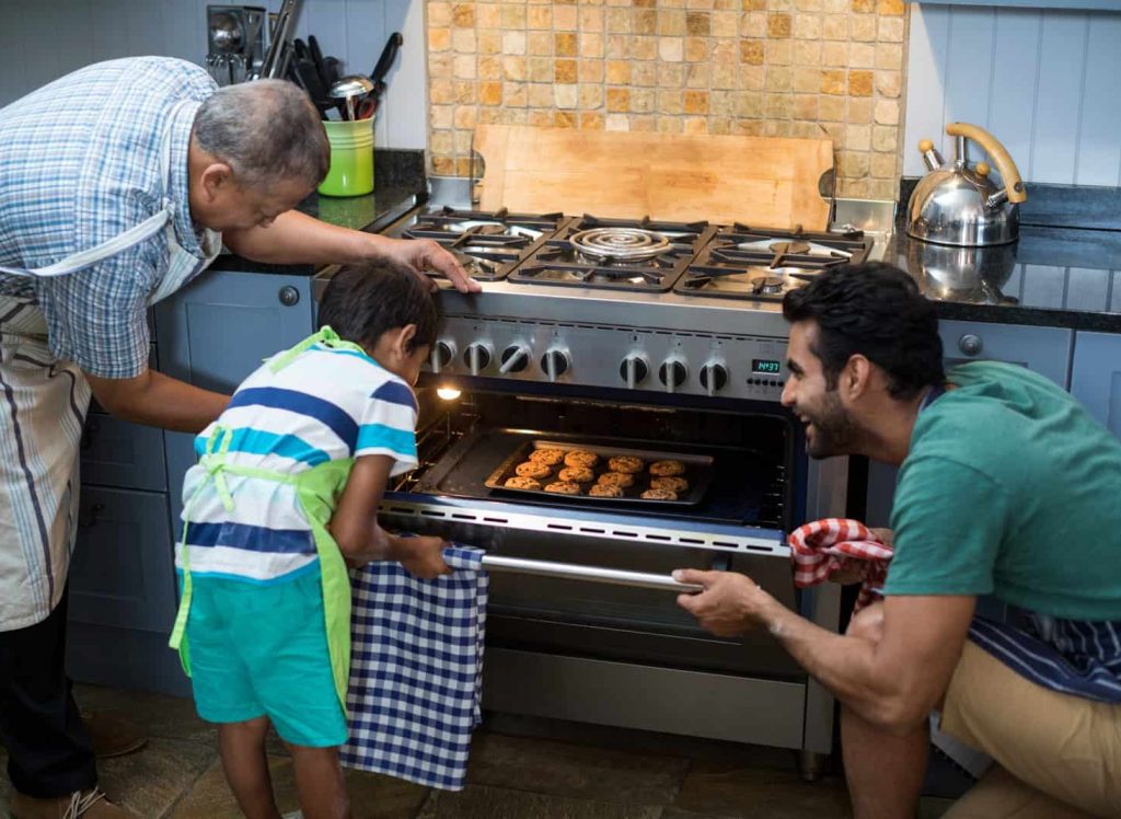 Family keeping cookies in oven at home